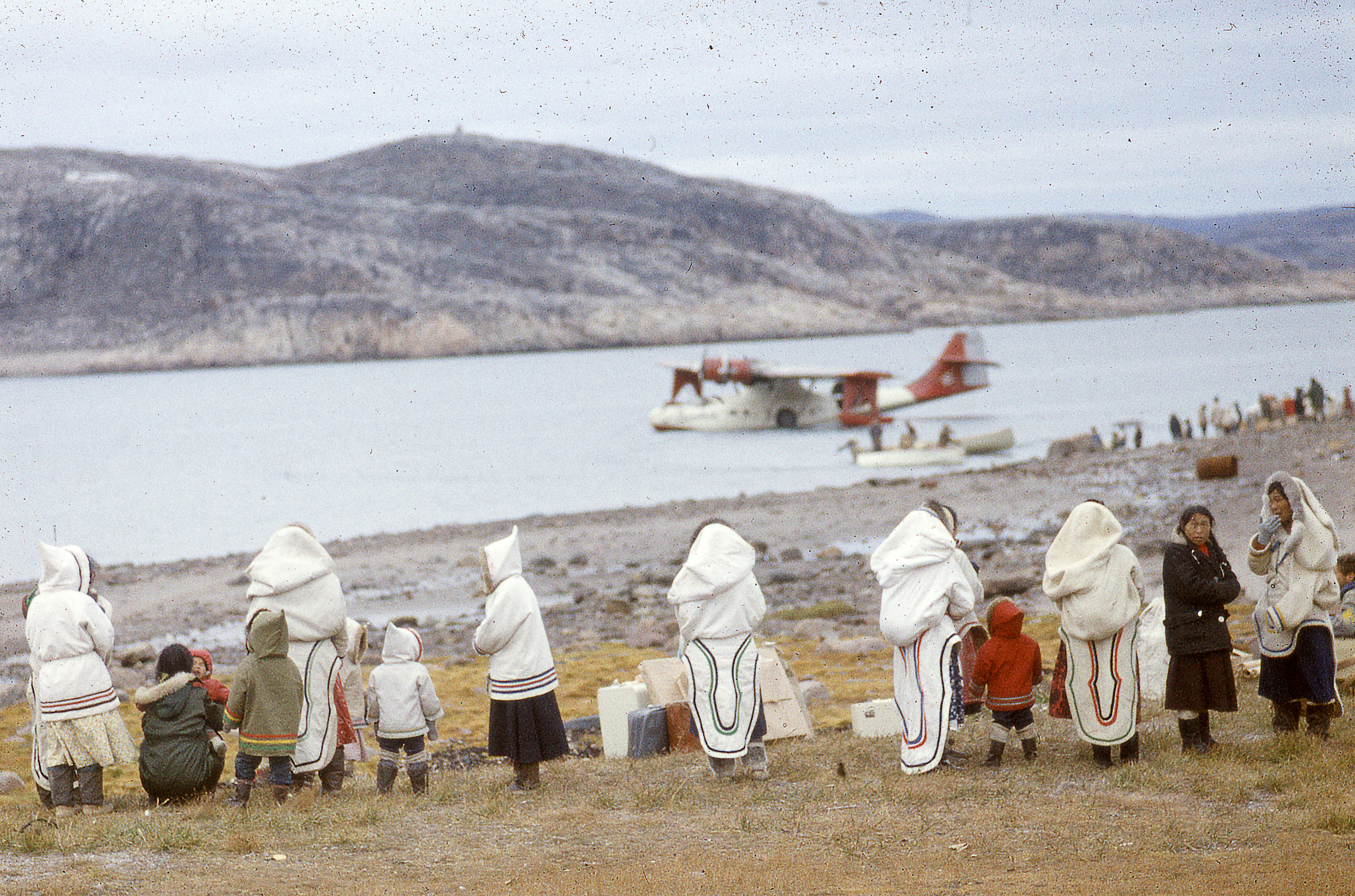 Several women and children watch the seaplane land in Cape Dorset, 1960
