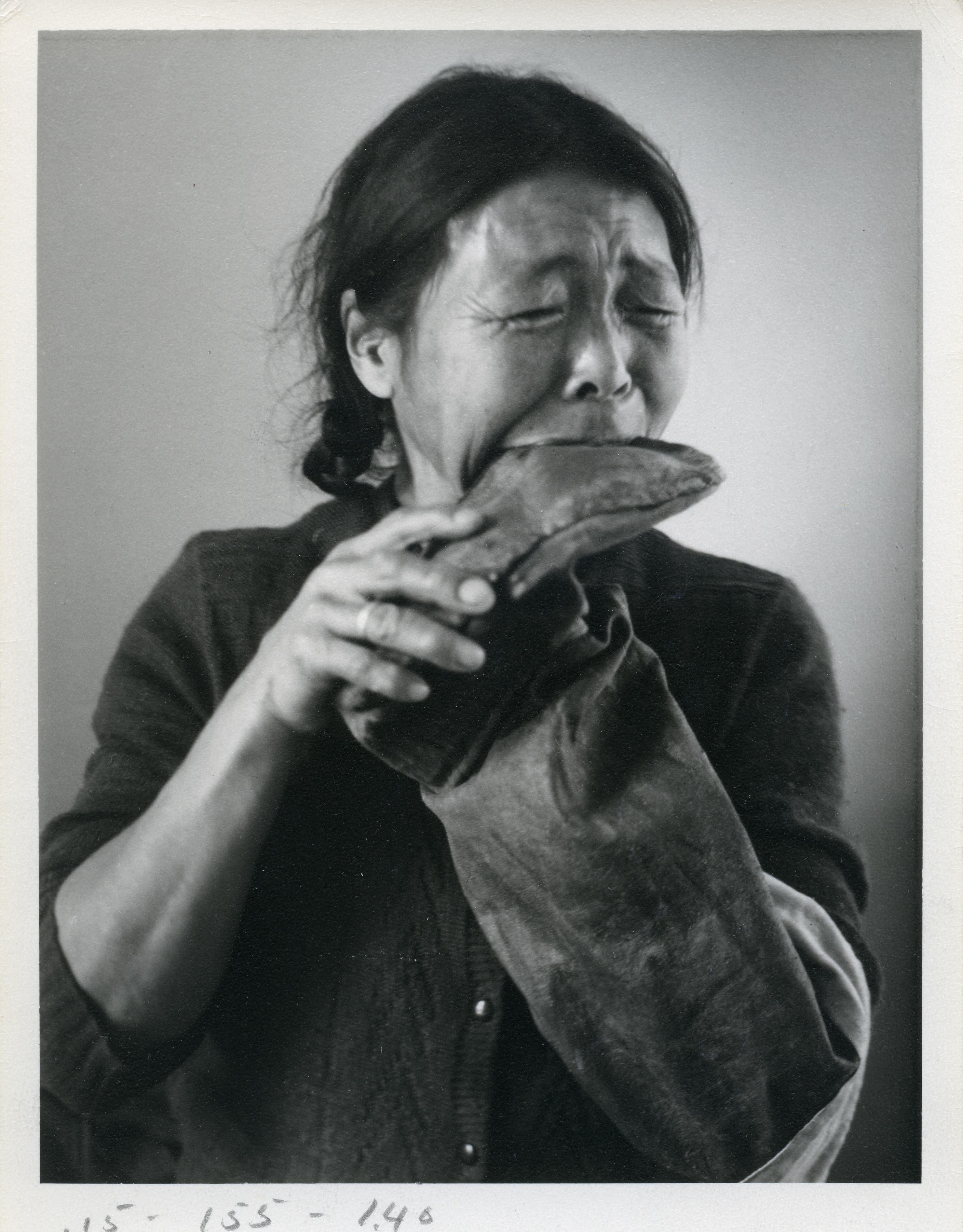Woman chewing seams of sealskin boot or kamik