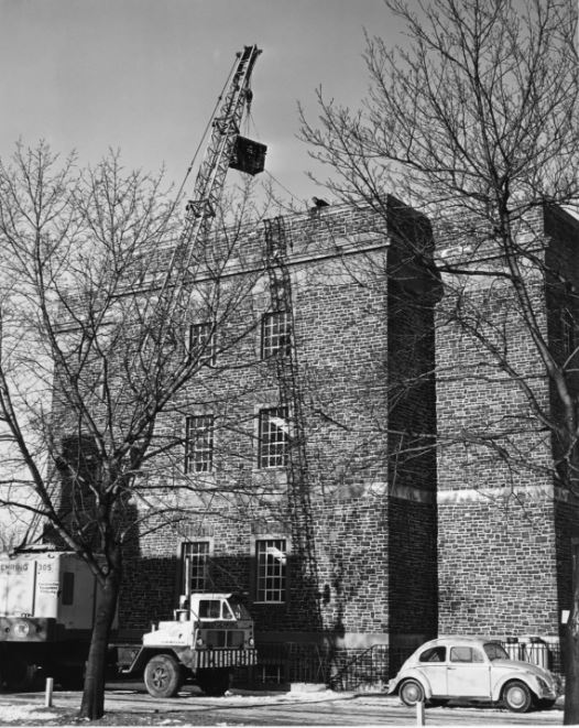 Photograph of crane hoisting IBM 1620 computer into place at the top of the Dunn Building, March 1964.